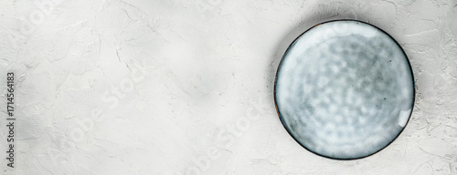Empty ceramic plate on light textured background, top view, free space for text