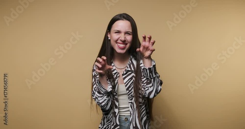 Cute girl plays around making funny faces and gestures against a yellow background in a playful setting