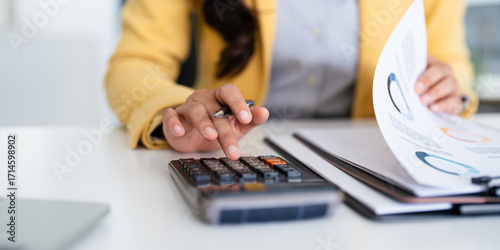 Close up young woman accountant hands , financial expert works in the office with documents, on a laptop, using a calculator .