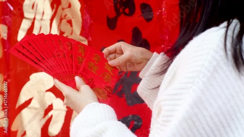 Hand holding red Chinese New Year money envelopes with golden calligraphy for holiday blessings and traditions