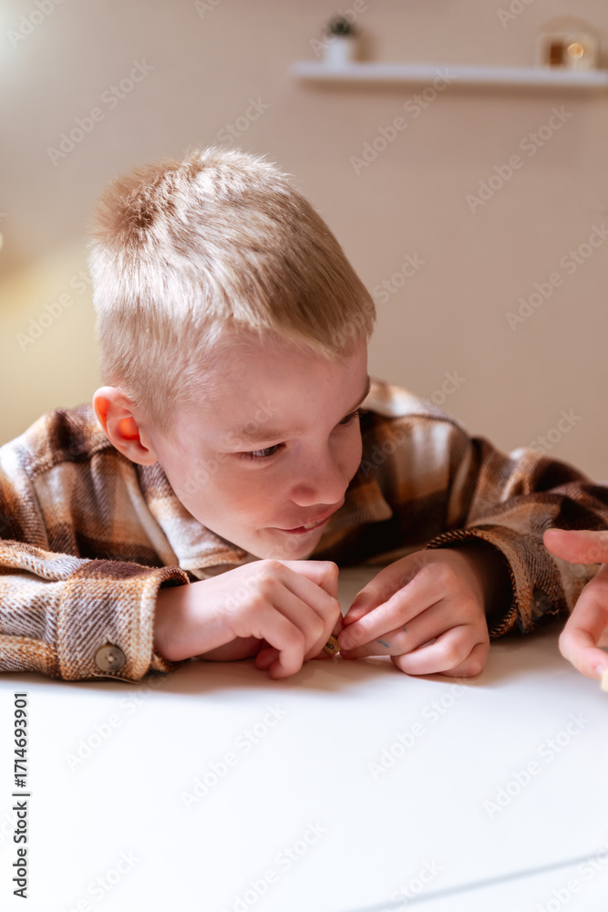Fototapeta premium A mother and her son with hearing aids share a joyful moment playing board games together. A heartwarming scene of inclusive family bonding, love, and adaptive play