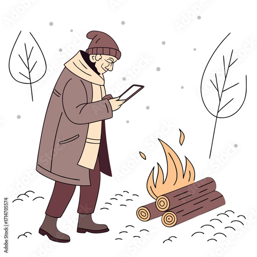 Man in winter coat and hat looking at tablet by a campfire in the snow