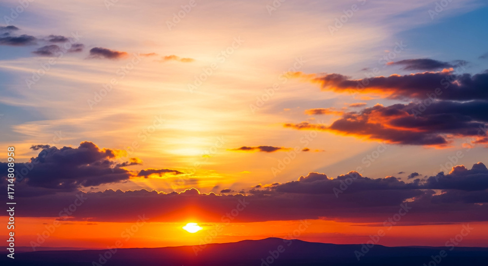 Obraz premium Vivid Sunset Over River and Rolling Hills with Radiant Sky and Silhouetted Trees