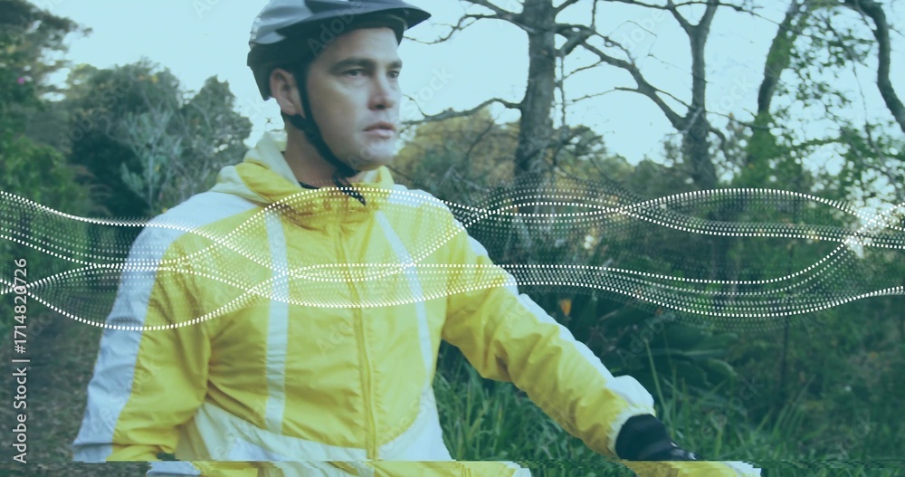 Fototapeta premium Riding light-skinned cyclist pedaling forest trail, with helmet, windbreaker, handlebars and gloves