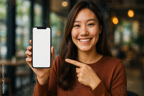 Happy woman points to blank smartphone screen for app promo