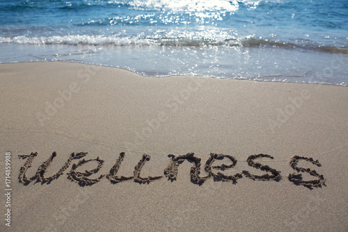 Word wellness handwritten on the caribbean sand.