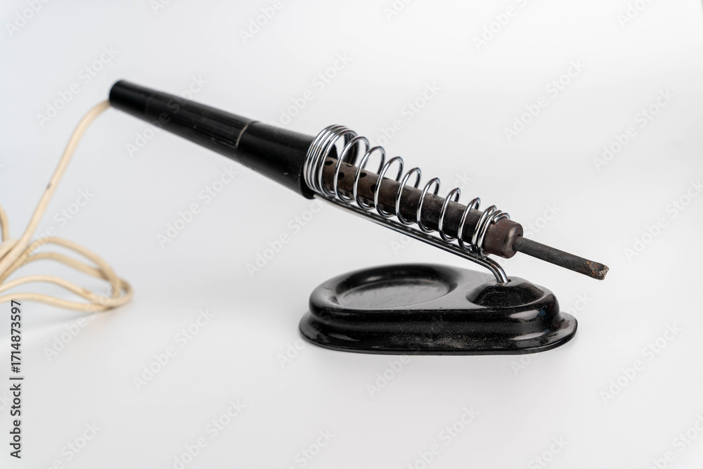 Naklejka premium Vintage soldering iron resting on a metal stand