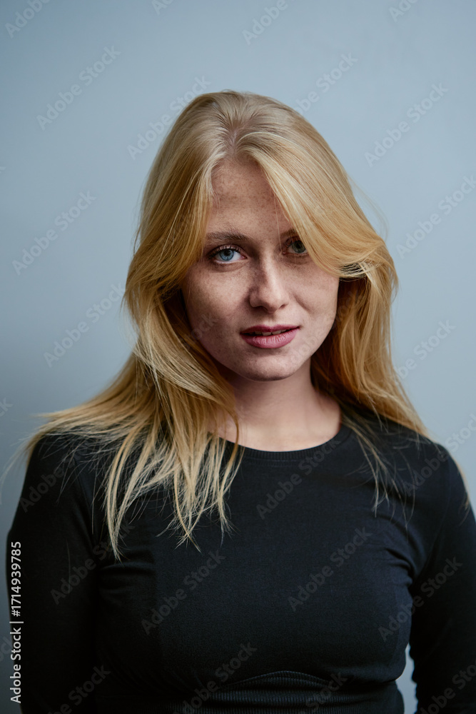 Naklejka premium Confident Young Woman in Black Top Posing Against Neutral Background
