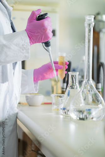 Scientist working with pipette in laboratory using protective gloves and glassware