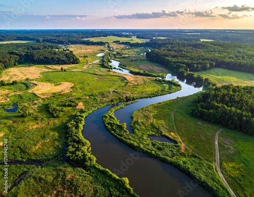 Aerial View of River Flowing Through Lush Green Forest Landscape Under Partly Cloudy Sky at Dusk