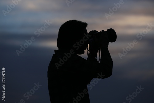 Silhouette of photographer with camera during sunset sky