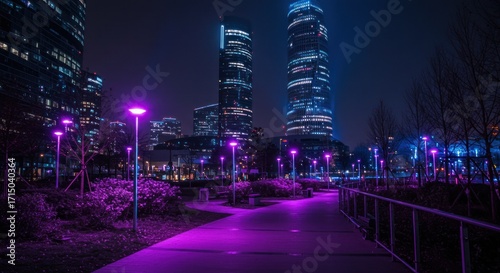 Cityscape at night featuring illuminated skyscrapers and a park with purple streetlights