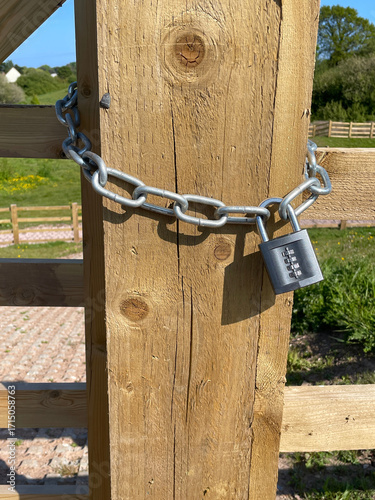 Close up of combination lock and steel chain on wooden fence post in countryside
