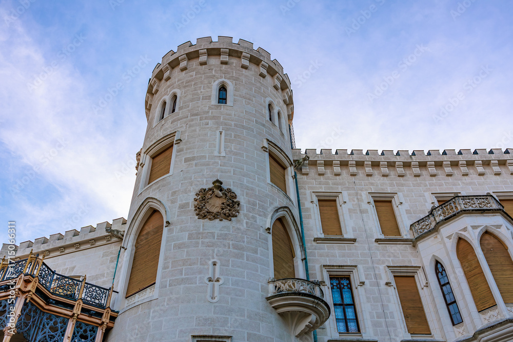Fototapeta premium Historic white stone castle tower against blue sky with gothic architecture