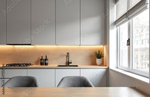 Modern kitchen interior with gray cabinets, warm wood accents. Features sleek black sink, induction stovetop, ambient LED lighting. Large window provides natural light, creating bright, minimalist