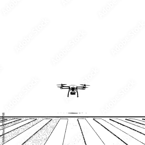 A drone hovers above a field with parallel lines creating a stark contrast in a black and white composition