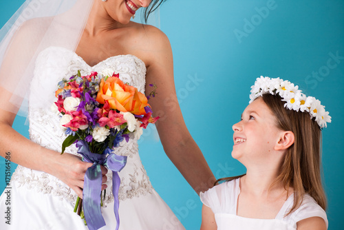 Happy Little Flower Girl Standing with Bride in Wedding Dress