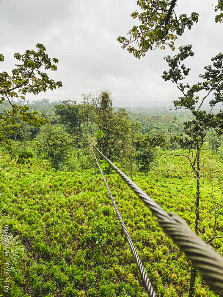 Fototapeta premium A long zipline cable stretches into the distance over a lush green valley in Costa Rica.