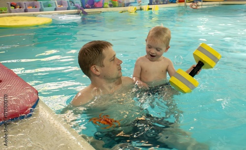 A man is holding a child in a pool