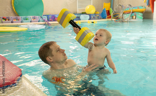 A man is holding a child in a pool