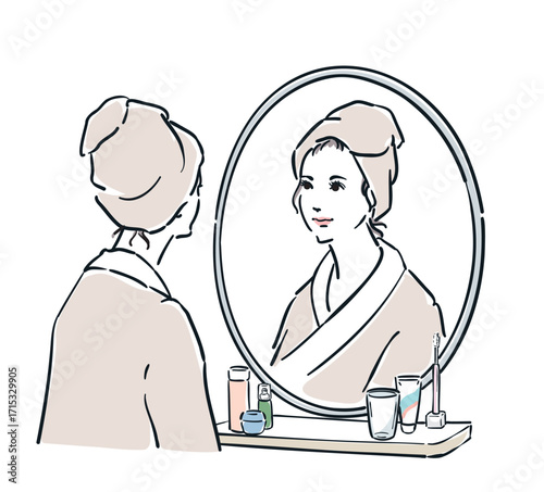鏡の前に立つバスローブ姿の女性