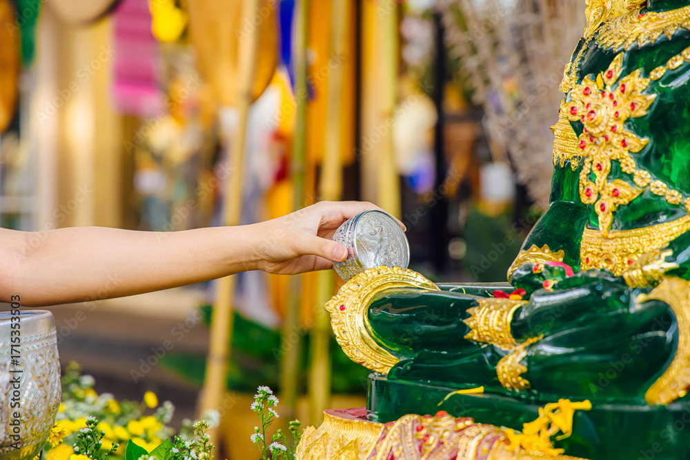 Φωτογραφία Buddhist Ritual of Pouring Water: A serene ceremony unfolds as a hand gracefully pours water over a gleaming statue, embodying a solemn act of reverence and spirituality