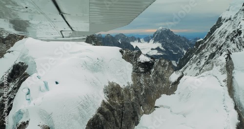 Aerial shot of snowy peaks in Alaska. Flying small plane along Denali National Park high mountains