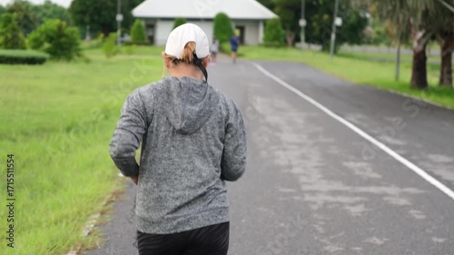 Video of Asian female athlete jogging in slow motion during morning park workout. Promotes active lifestyle, cardio health, and outdoor fitness recovery.