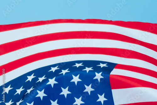 The US flag is waving in the wind.Close-up of the American flag hanging against a clear blue sky.