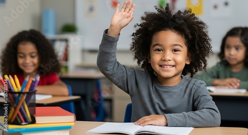 Mixed-race Afro Asian child raising hand in classroom, portrait of school student with books and crayons at desk, education and diversity concept