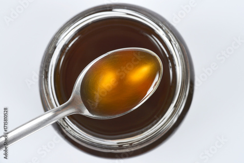 Spoonful of dark honeyA spoonful of dark honey hovering over an open jar of honey
