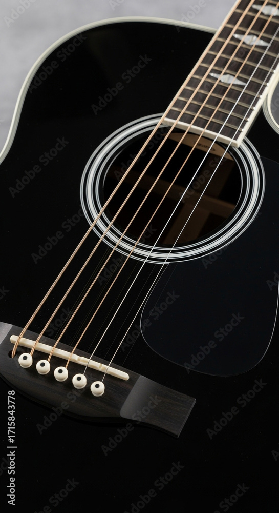 Fototapeta premium Stunning black acoustic guitar close-up reveals polished wood and gleaming strings, ready for melody.