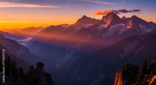 Majestic mountains bathed in the warm glow of a vibrant sunset, with light rays piercing through the valley.