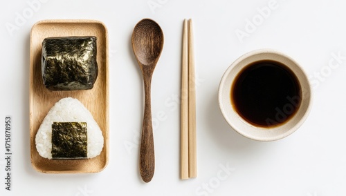 Two onigiri rice balls, wooden tray, spoon, chopsticks, soy sauce