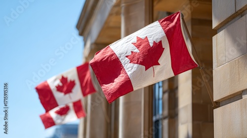 Multiple canadian flags are gently waving in the wind, attached to a light colored stone building facade under a clear blue sky, creating a patriotic and nationalistic scene