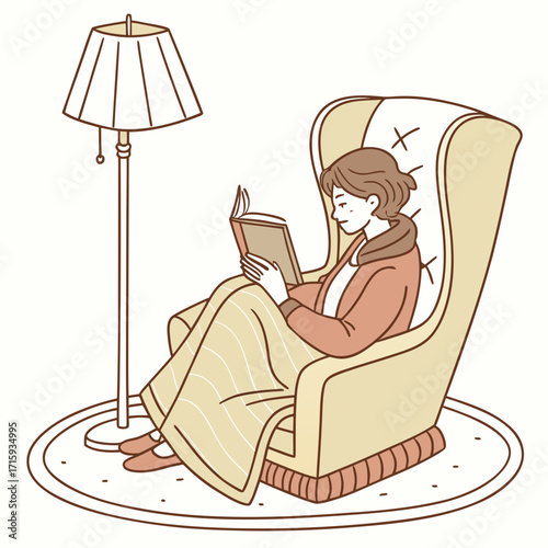 Cozy woman reading a book under a lamp while wrapped in a blanket in a comfortable armchair