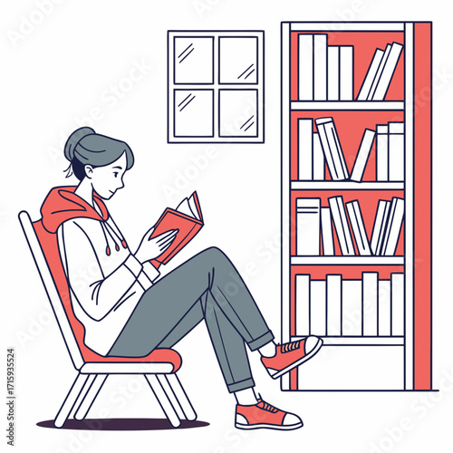 Young woman in casual clothing relaxing on a chair reading a book next to a bookshelf and window