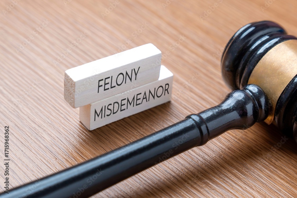 Naklejka premium A judge’s gavel next to wooden blocks labeled Felony and Misdemeanor. Legal terms, criminal charges, and judicial concepts in law and justice concept.
