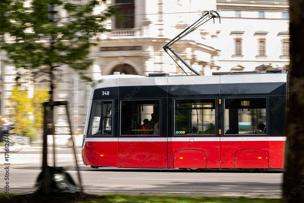 Fototapeta premium Red and Black Tram Passing Through Vienna's Historic Streets on a Bright and Sunny Day