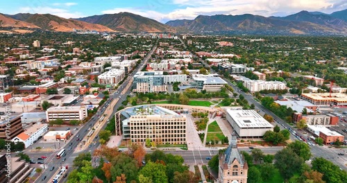 Lovely panorama of Salt Lake City with lush greenery. Drone footage over the lively city approaching the stunning mountains at backdrop.