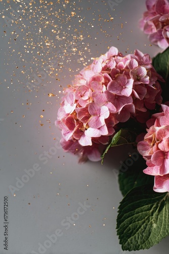 Pink hydrangeas with gold glitter falling on a grey background