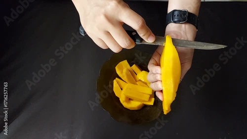 Hands Cutting Ripe Mango Slices on Plate for Tropical Fruit Preparation