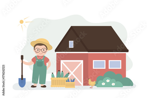 Happy boy with a shovel in his hand stands near the barn. Farmhouse, cute little farmer. Rural view, agriculture, eco and organic food.