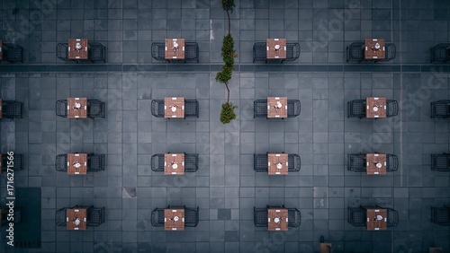 Aerial view of a restaurant patio with tables and chairs arranged in rows, separated by a thin line of greenery.