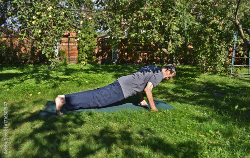 A 76-year-old man is doing push-ups in the garden.