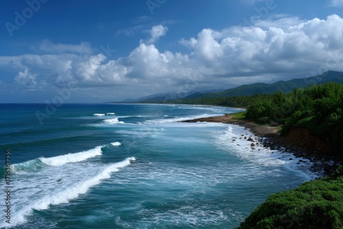 Turquoise ocean meets lush coastline under cloudy sky waves crash on rocky shore green hills in the background