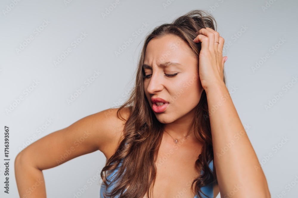 Obraz premium Woman experiencing discomfort while touching her shoulder in a studio setting during daytime