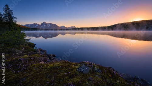 Misty mountain lake at sunrise with golden sky reflection