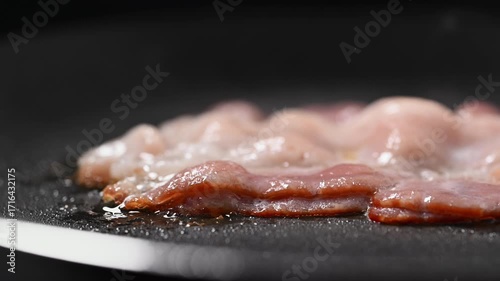 Crispy bacon sizzling in a pan, close-up shot. Perfect for food advertisements, cooking shows, and background footage. Appetizing and high-quality 4K slow-mo video.