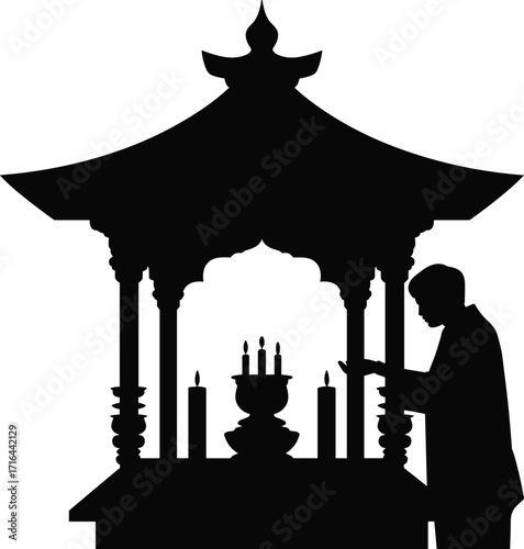 Silhouette of a person lighting candles at an altar